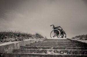 Foto van een trap van onderaf genomen. Bovenaan staat een rolstoel.
